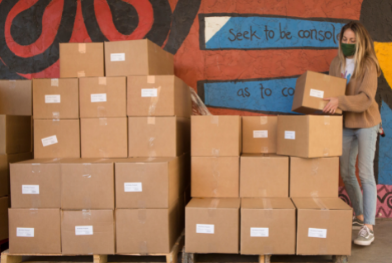 woman standing grabbing box from large pile of boxes